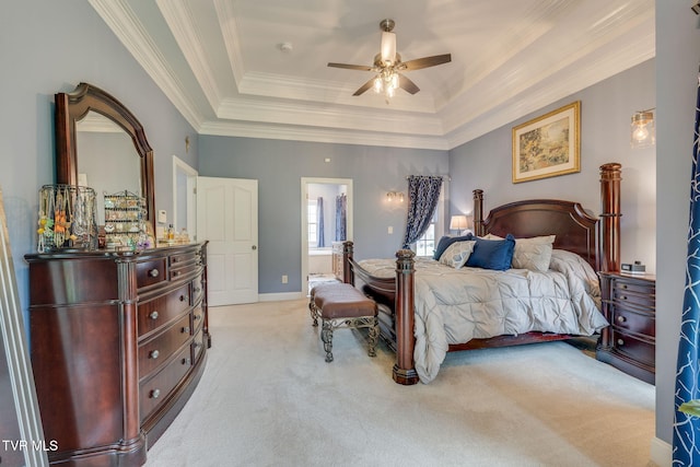 bedroom with light colored carpet, a raised ceiling, baseboards, ornamental molding, and ensuite bath