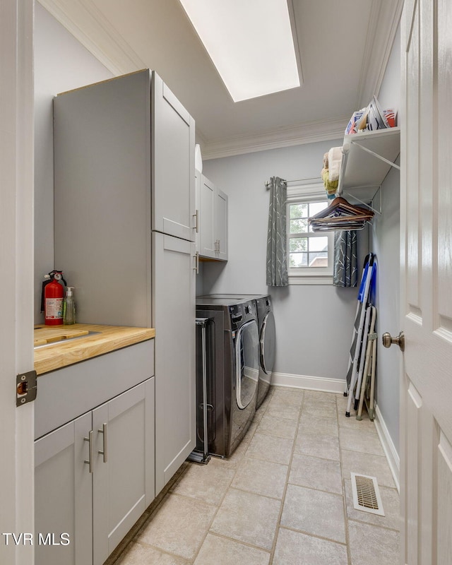 laundry area featuring light tile patterned floors, visible vents, separate washer and dryer, ornamental molding, and cabinet space