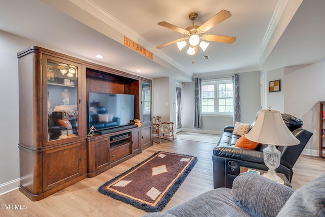 living room featuring baseboards, light wood-type flooring, a ceiling fan, and crown molding