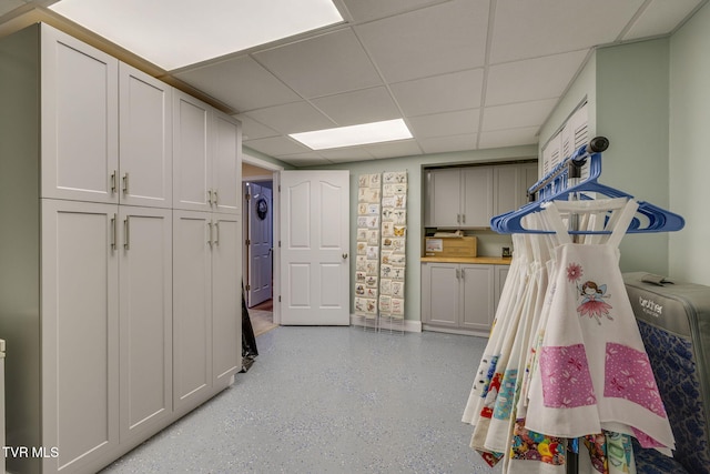 interior space with a drop ceiling and baseboards