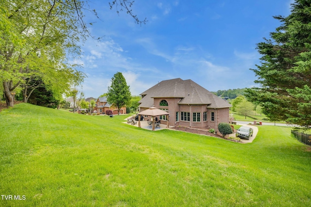 rear view of property with a gazebo, a yard, and brick siding