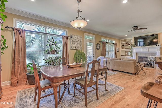 dining space featuring a tile fireplace, crown molding, and recessed lighting