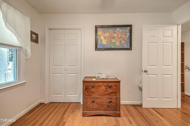 bedroom with baseboards, light wood finished floors, and a closet