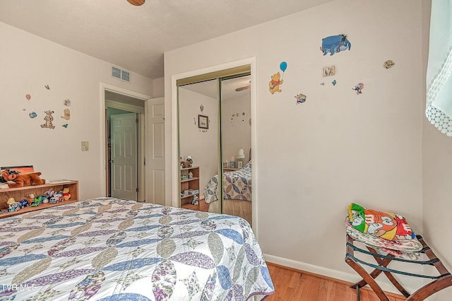 bedroom featuring visible vents, light wood-style flooring, baseboards, and a closet