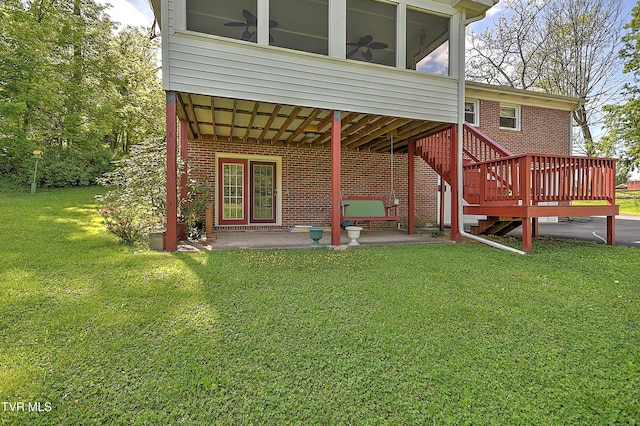 rear view of property featuring a deck, brick siding, stairs, a patio area, and a lawn
