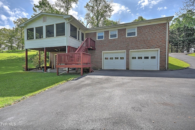 view of front of property featuring brick siding, a garage, a sunroom, and aphalt driveway