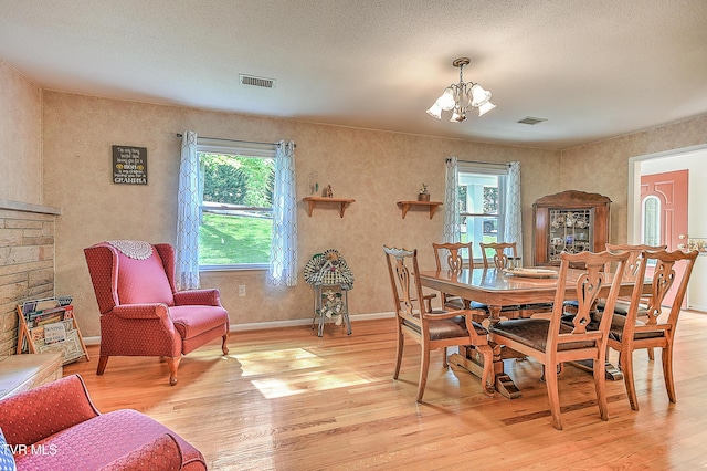 dining space with visible vents, light wood-style flooring, baseboards, and a notable chandelier