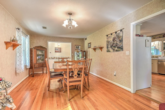 dining area featuring visible vents, a textured wall, and light wood-type flooring
