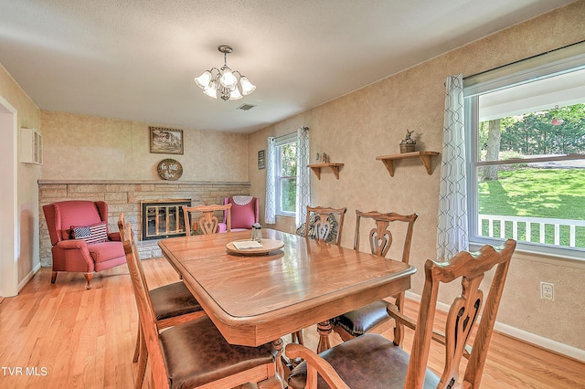 dining room with visible vents, a fireplace, light wood-type flooring, baseboards, and an inviting chandelier