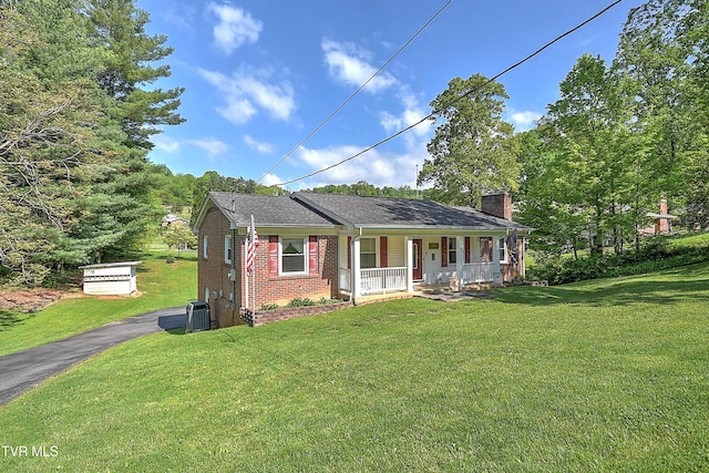 bungalow-style house featuring brick siding, a chimney, covered porch, and a front yard