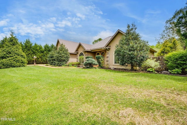 view of front of home with stucco siding, metal roof, and a front lawn