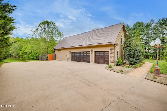 view of property exterior featuring metal roof, concrete driveway, and stucco siding
