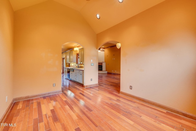 spare room with recessed lighting, a sink, high vaulted ceiling, light wood-type flooring, and arched walkways
