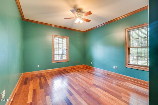 empty room featuring a ceiling fan, hardwood / wood-style flooring, a healthy amount of sunlight, and ornamental molding