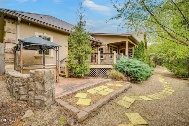 back of house with a patio, a wooden deck, metal roof, ceiling fan, and stucco siding