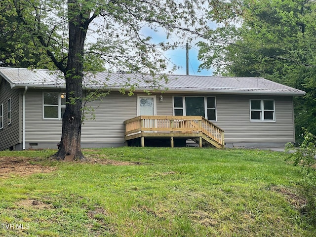rear view of property featuring metal roof, a deck, and a yard