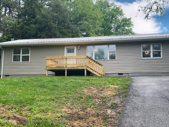 view of front of property with a deck, a front lawn, metal roof, and crawl space