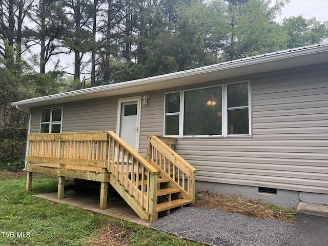 rear view of house with a wooden deck, metal roof, and crawl space