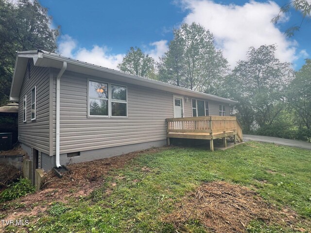 rear view of house with crawl space, a wooden deck, and a lawn