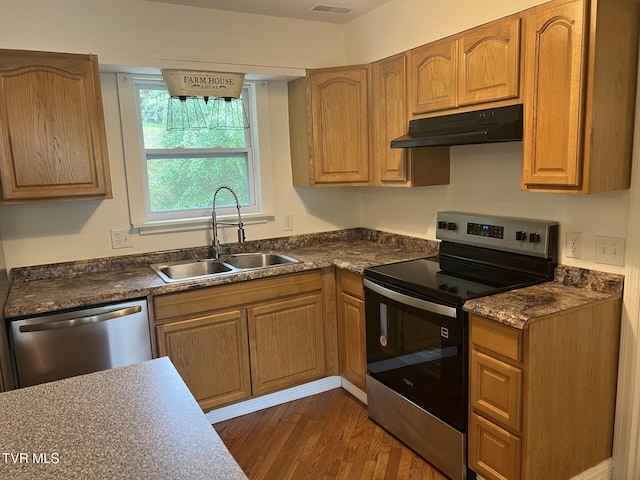 kitchen featuring a sink, dark countertops, stainless steel appliances, under cabinet range hood, and dark wood finished floors