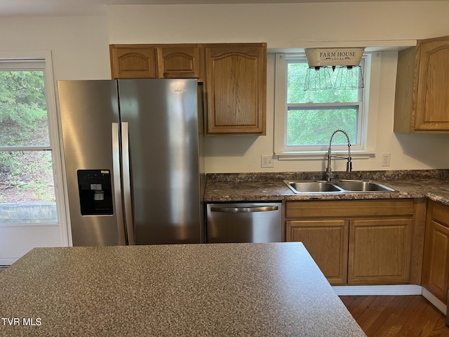 kitchen featuring dark countertops, a sink, appliances with stainless steel finishes, and a wealth of natural light