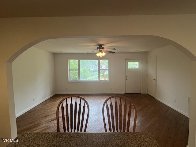 interior space featuring arched walkways, ceiling fan, wood finished floors, and plenty of natural light