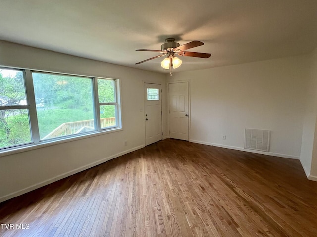 empty room with visible vents, ceiling fan, wood finished floors, and baseboards