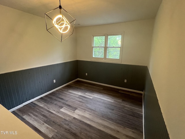 unfurnished room featuring a chandelier, wainscoting, wood finished floors, and baseboards