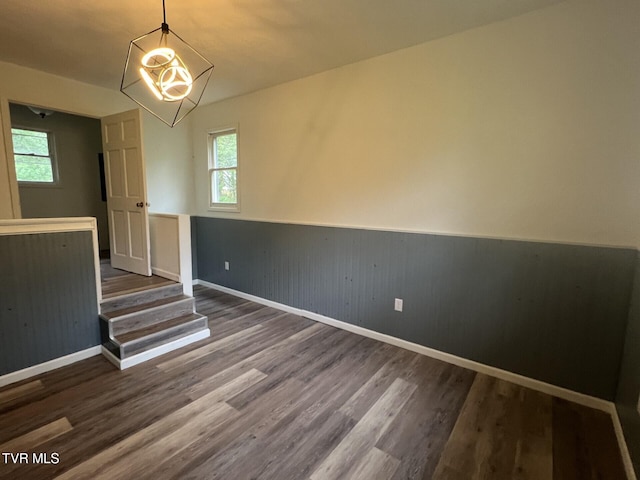 unfurnished room with a wainscoted wall, baseboards, wood finished floors, and a wealth of natural light
