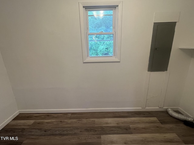 empty room featuring baseboards, dark wood-style flooring, and electric panel