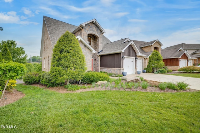 view of front of house featuring an attached garage, driveway, a front lawn, and stone siding