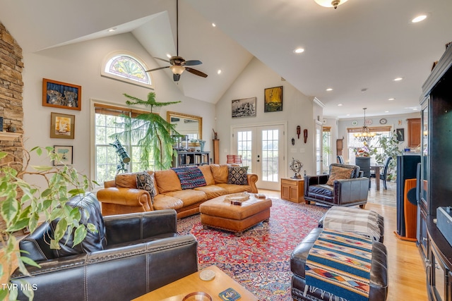 living room with light wood finished floors, high vaulted ceiling, french doors, ceiling fan with notable chandelier, and recessed lighting