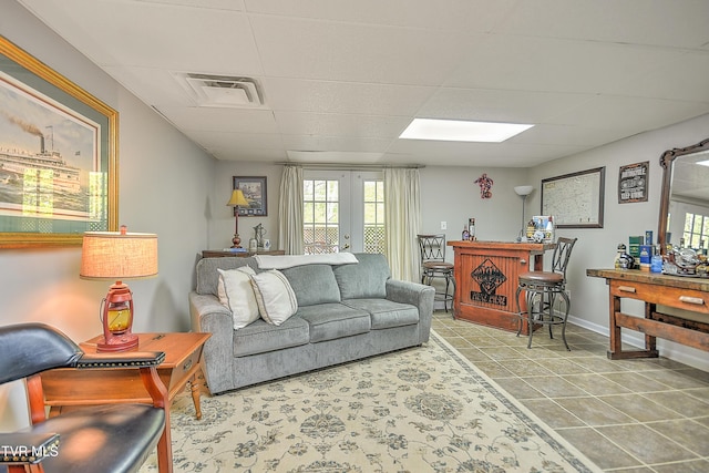 living room with a paneled ceiling, visible vents, french doors, and baseboards