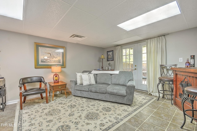 living room featuring tile patterned flooring, a paneled ceiling, and visible vents