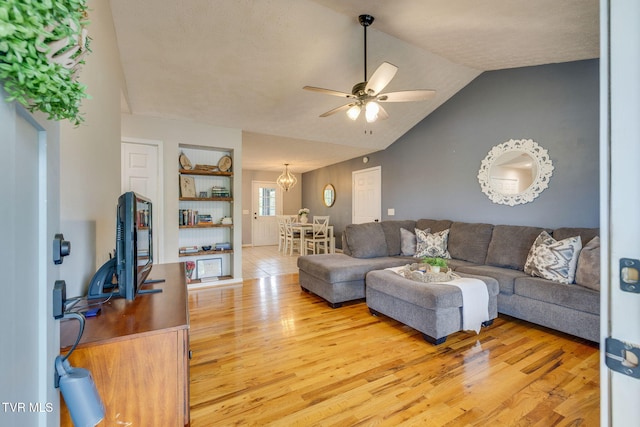 living area with a ceiling fan, light wood finished floors, and vaulted ceiling