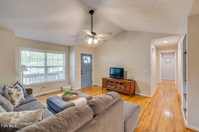 living room with lofted ceiling, a textured ceiling, ceiling fan, and light wood-type flooring