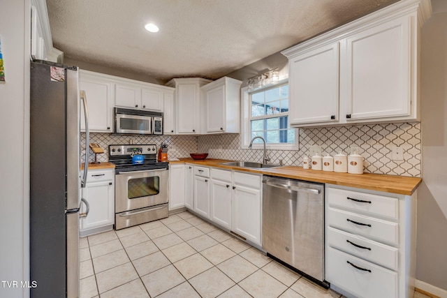 kitchen with white cabinetry, butcher block counters, appliances with stainless steel finishes, and a sink
