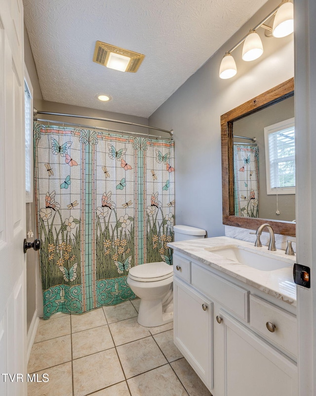 full bath featuring a tile shower, visible vents, toilet, vanity, and tile patterned flooring