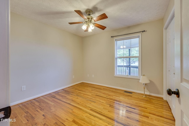 spare room featuring visible vents, a ceiling fan, light wood-style floors, and a textured ceiling