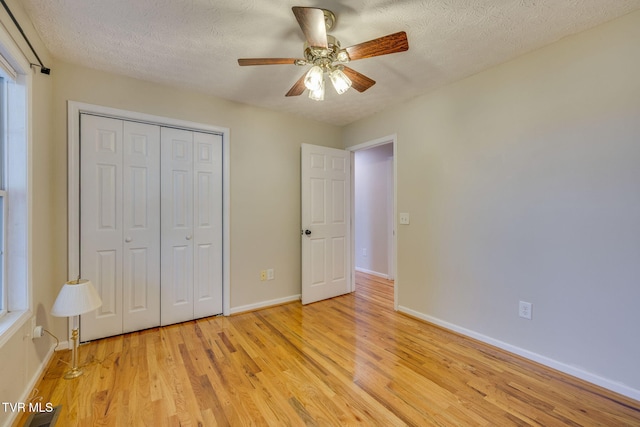 unfurnished bedroom featuring baseboards, light wood-style floors, a textured ceiling, and a closet