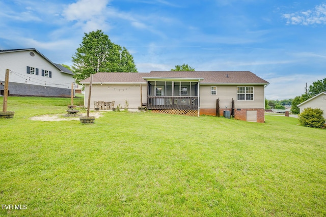 rear view of property featuring an outdoor fire pit, central AC unit, a sunroom, and a lawn
