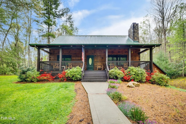 view of front of house featuring a porch, a front yard, a chimney, and metal roof