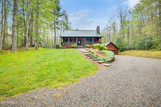 chalet / cabin featuring an outdoor structure, a front lawn, a chimney, metal roof, and a porch