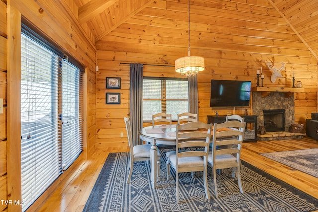 dining room with wood walls, a healthy amount of sunlight, lofted ceiling, and hardwood / wood-style floors