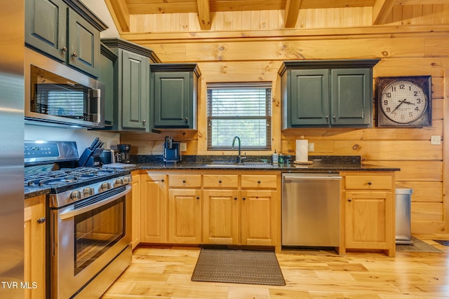 kitchen featuring a sink, beamed ceiling, wooden walls, light wood-style floors, and stainless steel appliances