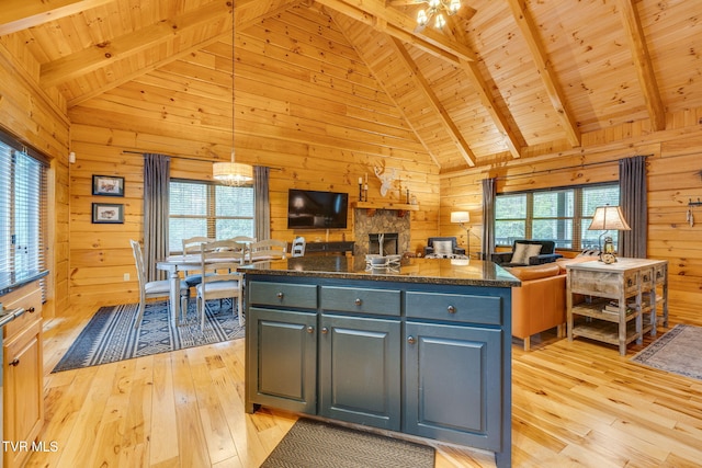 kitchen featuring wood walls, wood ceiling, open floor plan, and beamed ceiling