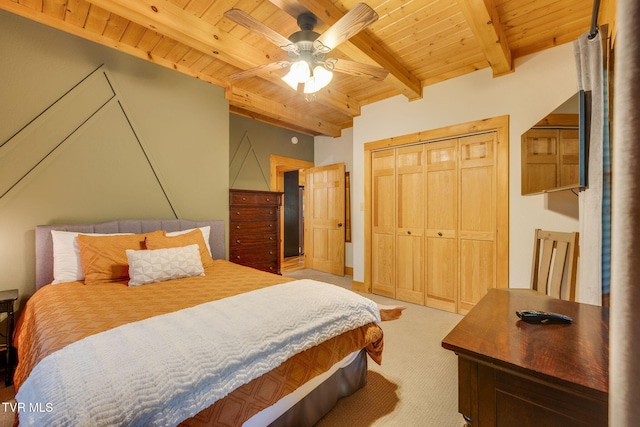 bedroom featuring light carpet, a ceiling fan, beamed ceiling, wood ceiling, and a closet