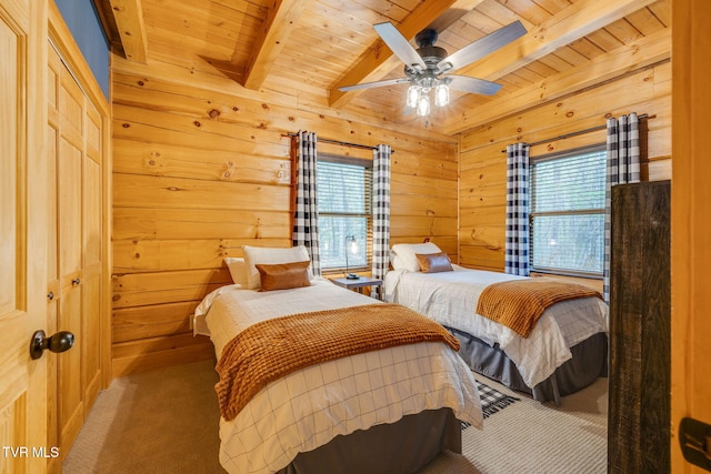 carpeted bedroom with wood walls, wood ceiling, a ceiling fan, and beamed ceiling