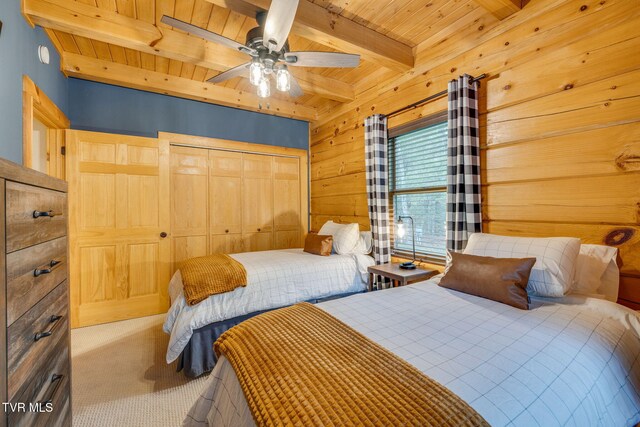 carpeted bedroom with ceiling fan, wood walls, wooden ceiling, beamed ceiling, and a closet