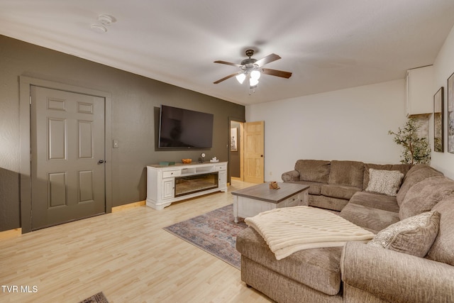 living room with baseboards, a ceiling fan, light wood finished floors, and a fireplace